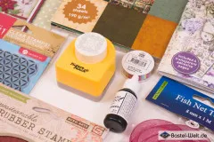 Detailausschnitt mit gemusterter Bastelstanze, Bandspule und grüner Archival-Stempelfarbe.